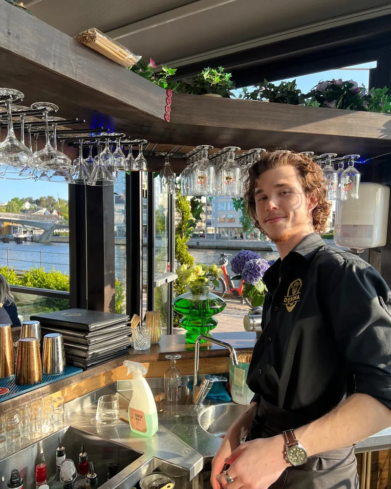 Bartender i utebaren, med elva i bakgrunnen