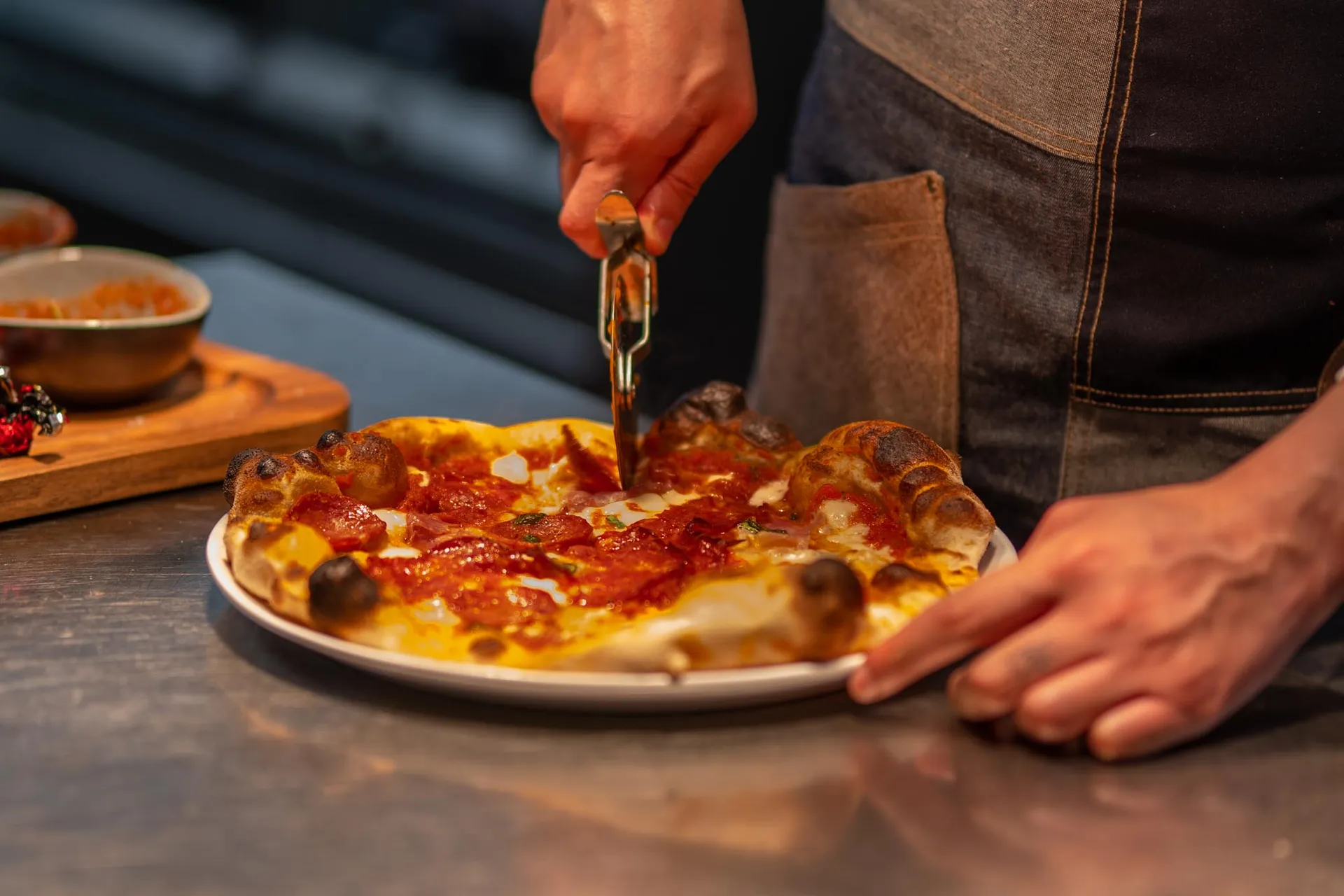 Kokk deler opp en nystekt pizza